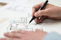 Architectural drawings spread across a desk with a pencil and ruler, illustrating the detailed 2D plans and elevations created by DWG Plans Sussex.